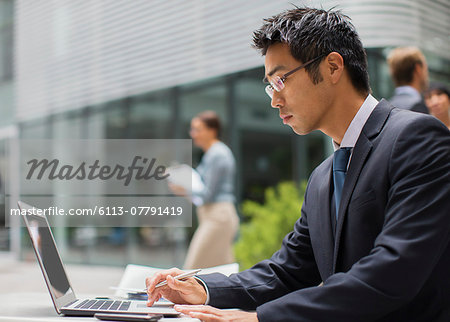 Businessman working on laptop outside of office building