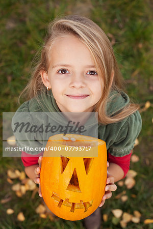 Autumn portrait with a Halloween pumpkin jack-o-lantern - little girl looking up