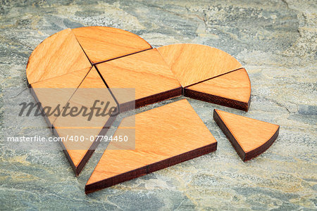 heart version of tangram, a traditional Chinese Puzzle Game made of different wood parts to build abstract figures from them, on  a slate rock background