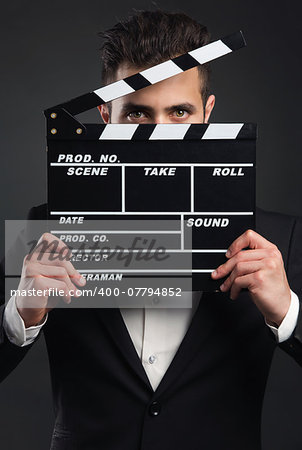 Studio portrait of a young man with a suit and holding a clapboard