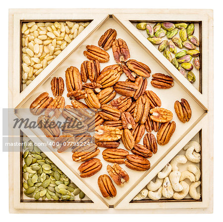 variety of nuts and seeds (pecan, cashew, pine, pistachio, pumpkin) in a geometrical wood tray
