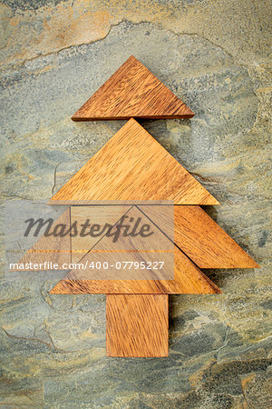 abstract picture of a Christmas tree built from seven tangram wooden pieces over a slate rock background, Christmas holiday concept, artwork created by the photographer