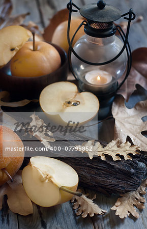 Ripe asian pears, lantern with candle and fall leaves on wooden table. Autumn concept. Selective focus.