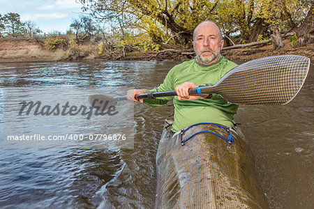 senior male paddler training in a fast sea kayak used in adventure racing, fall scenery, Poudre RIver in Fort Collins, Colorado, bow view