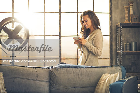 Young woman writing sms in loft apartment