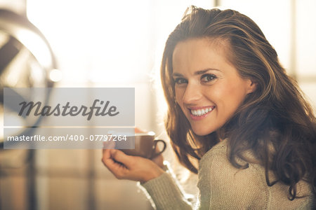 Portrait of happy young woman with cup of hot beverage