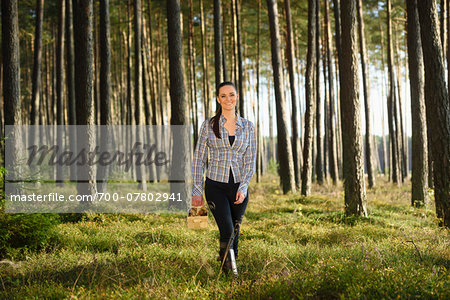 Portrait of Young Woman Collecting Mushrooms in Scots Pine (Pinus sylvestris) Forest in Early Autumn, Bavaria, Germany