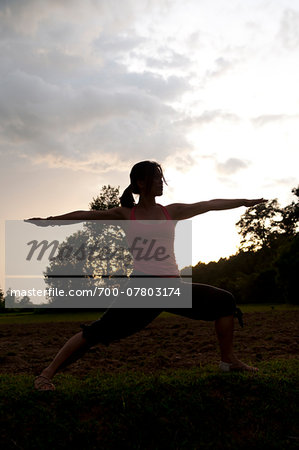 Young woman practising yoga outdoors at sunset, showing the pose virabhadrasana II, Angkor, Cambodia, Indochina, Southeast Asia, Asia