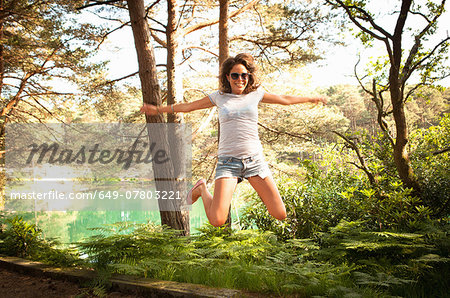 Mid adult woman jumping mid air, Blue Pool, Wareham, Dorset, UK