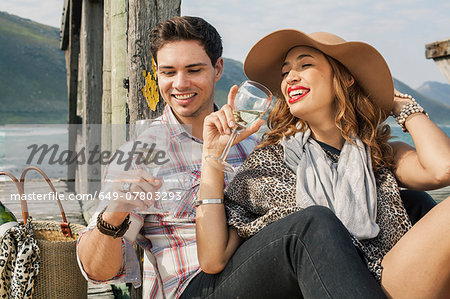 Young couple drinking wine on old pier, Cape Town, Western Cape, South Africa Young couple drinking wine on old pier, Cape Town, Western Cape, South Africa
