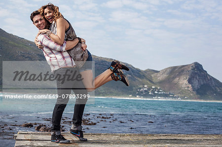 Young couple hugging on coastal pier, Cape Town, Western Cape, South Africa