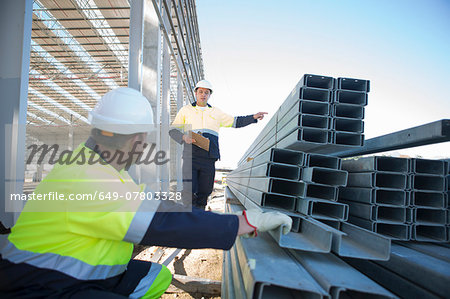 Builder and site manager checking girders on construction site