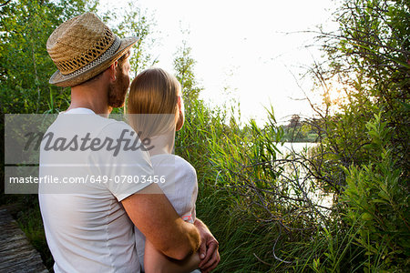 Romantic mid adult couple watching lakeside sunset