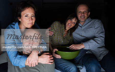 Two mature couples watching TV with snack bowls
