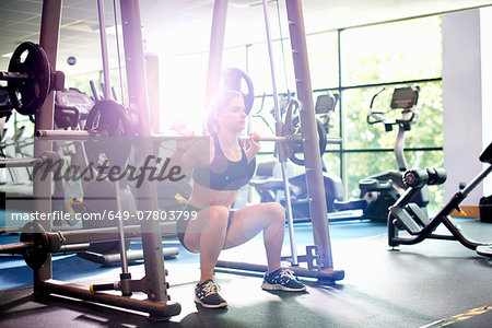 Young woman weight lifting with barbell