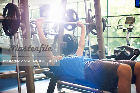 Young man weight lifting with barbell