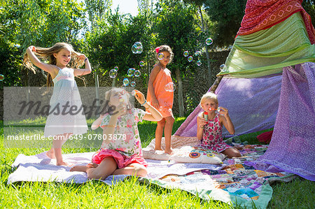 Girls blowing bubbles in summer garden party
