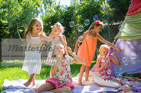 Girls blowing bubbles in summer garden party