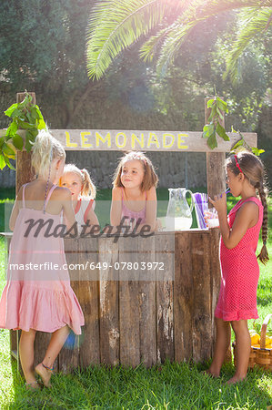 Four girls buying and selling at lemonade stand in park