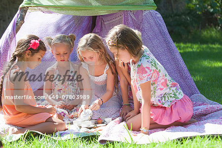 Five girls playing with toy tea set in garden