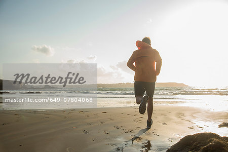 Mature man running on sand, along coastline