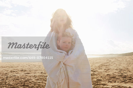 Portrait of two sisters wrapped in blanket on beach, Camber Sands, Kent, UK Portrait of two sisters wrapped in blanket on beach, Camber Sands, Kent, UK