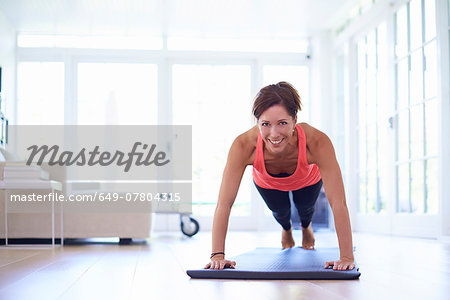 Mid adult woman doing press ups in living room