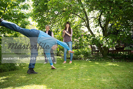 Grandparents and granddaughter doing acrobatics in garden