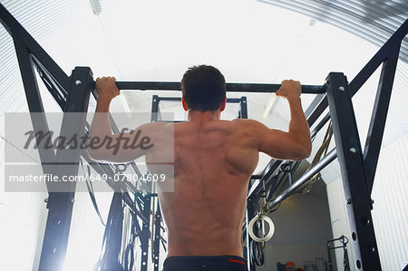 Crossfitter doing pull ups in gym