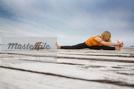 Mid adult woman practicing yoga on wooden sea pier