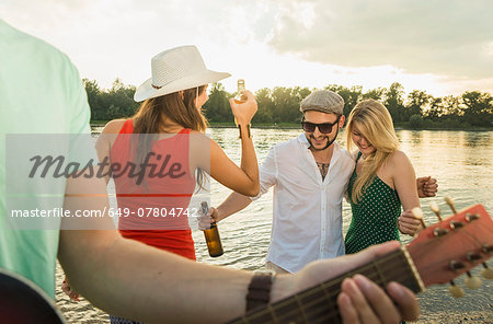 Group of friends with beer, guitar in foreground Group of friends with beer, guitar in foreground