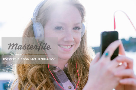 Close up portrait of young woman listening to music on headphones on street