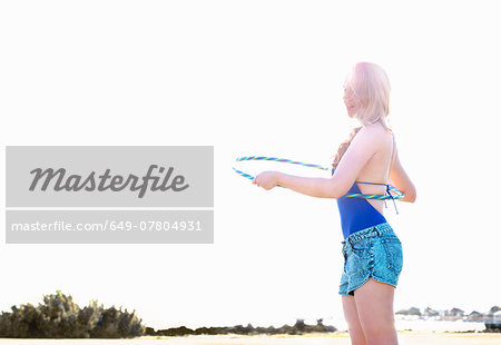 Young woman with hoola hoop on beach, Williamstown, Melbourne, Australia