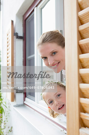 Mother and daughter peering through window