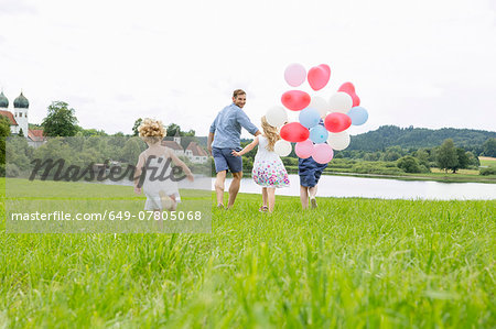 Family running through field with balloons