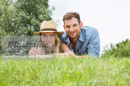 Mid adult couple lying on grass, portrait