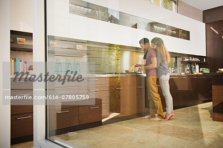 Loved up couple cooking on hob in kitchen