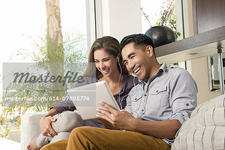 Couple on sitting room sofa looking at digital tablet