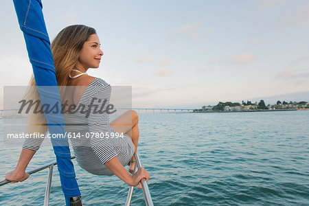 Mid adult woman sitting on railing on sailing boat