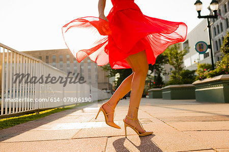 Waist down view of young woman twirling whilst wearing red dress