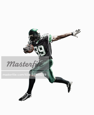 Studio shot of male football player running with ball