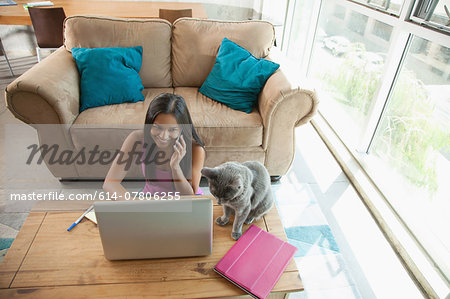 Woman on smartphone using laptop at home