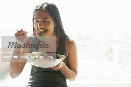 Woman eating salad at home