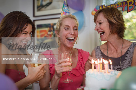 Three mature women at birthday party, laughing