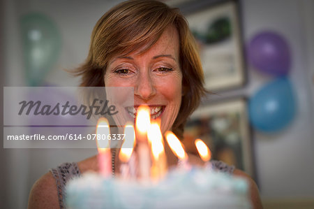 Mature woman holding birthday cake with candles