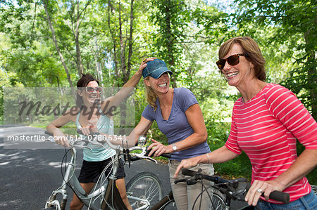 Three mature woman with bicycles along country road