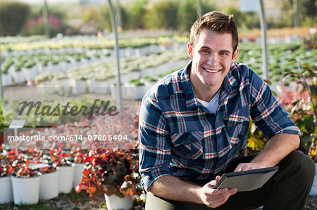 Portrait of young male worker using digital tablet in plant nursery polytunnel