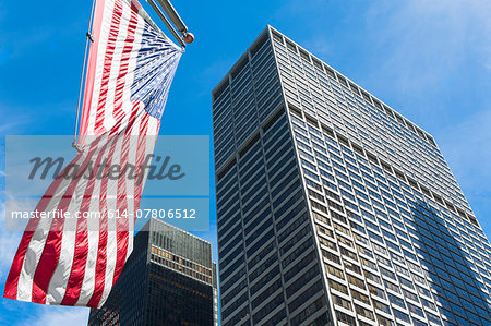 Low angled view of skyscrapers and American flag in financial district, Manhattan, New York, USA