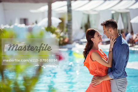 Couple standing face to face by swimming pool