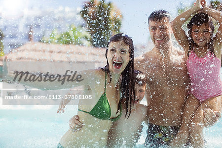 Family with two children splashing water and laughing in swimming pool